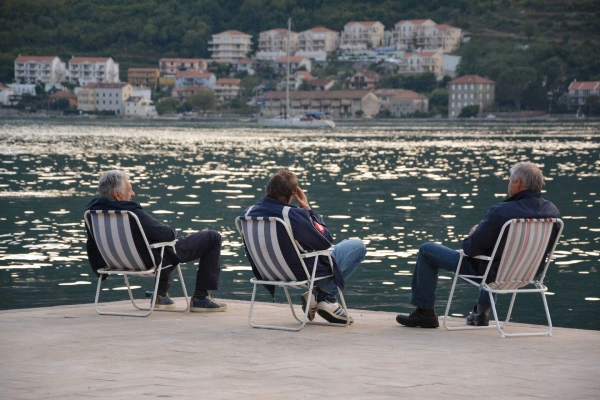 Locals sitting by the sea in the Bay of Kotor, facing the water